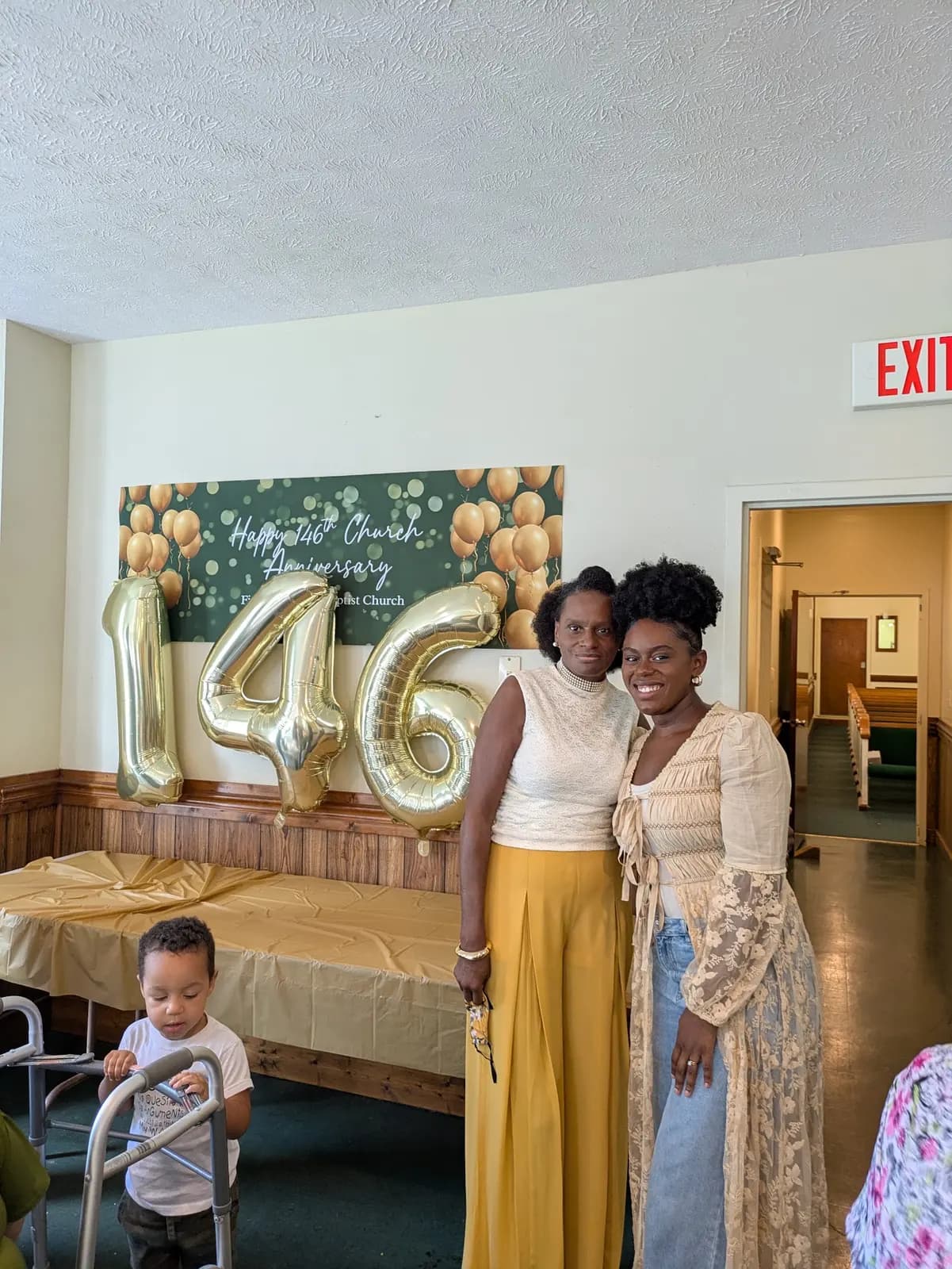 Two women and a little boy beside the 146 balloons at the anniversary celebration