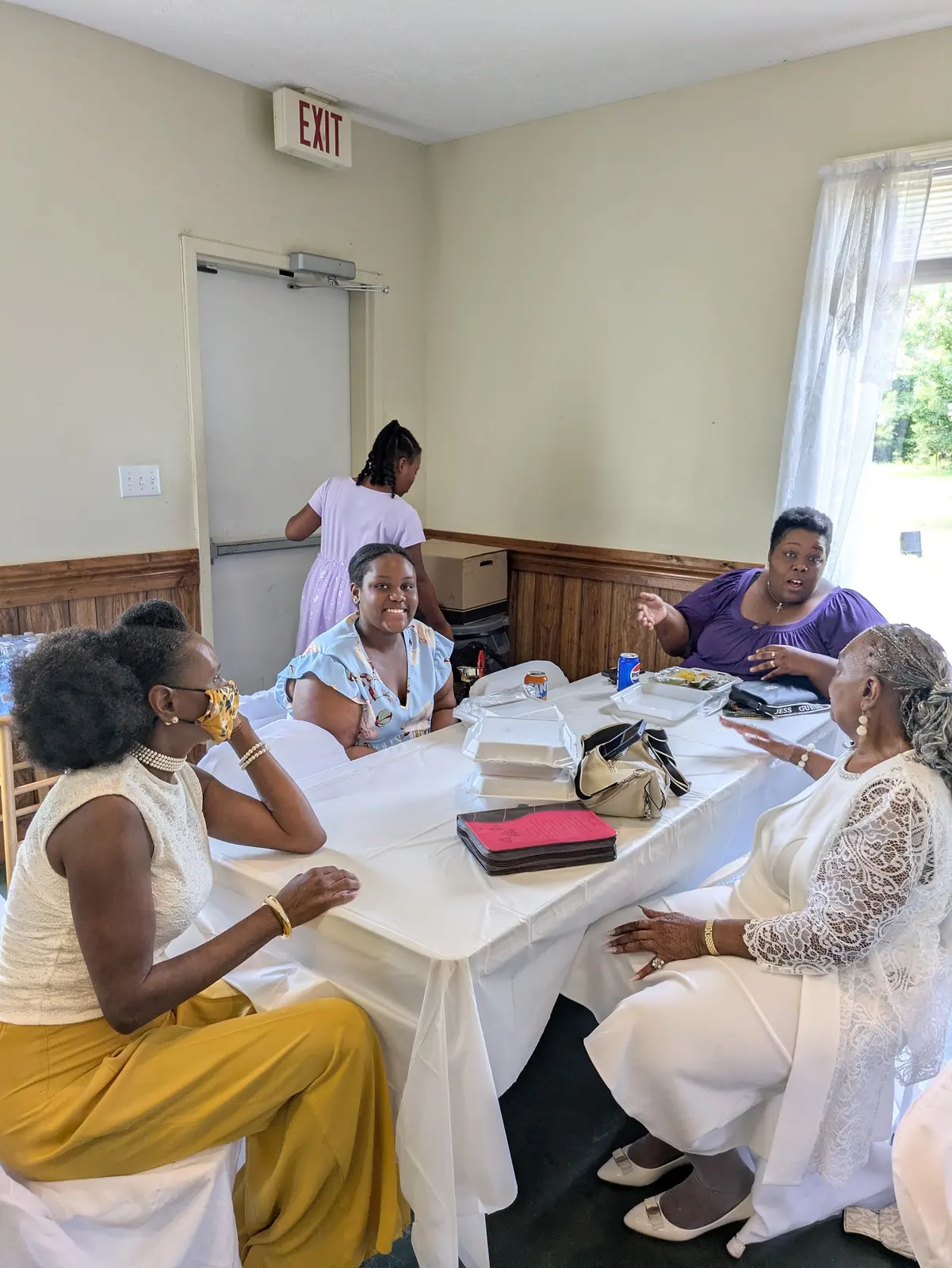 Members sharing a meal at white-clothed tables in the fellowship hall