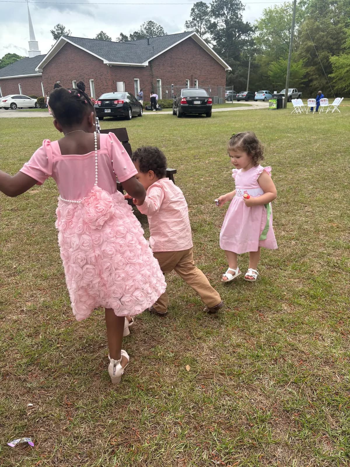 Children in Easter dresses playing on the church lawn