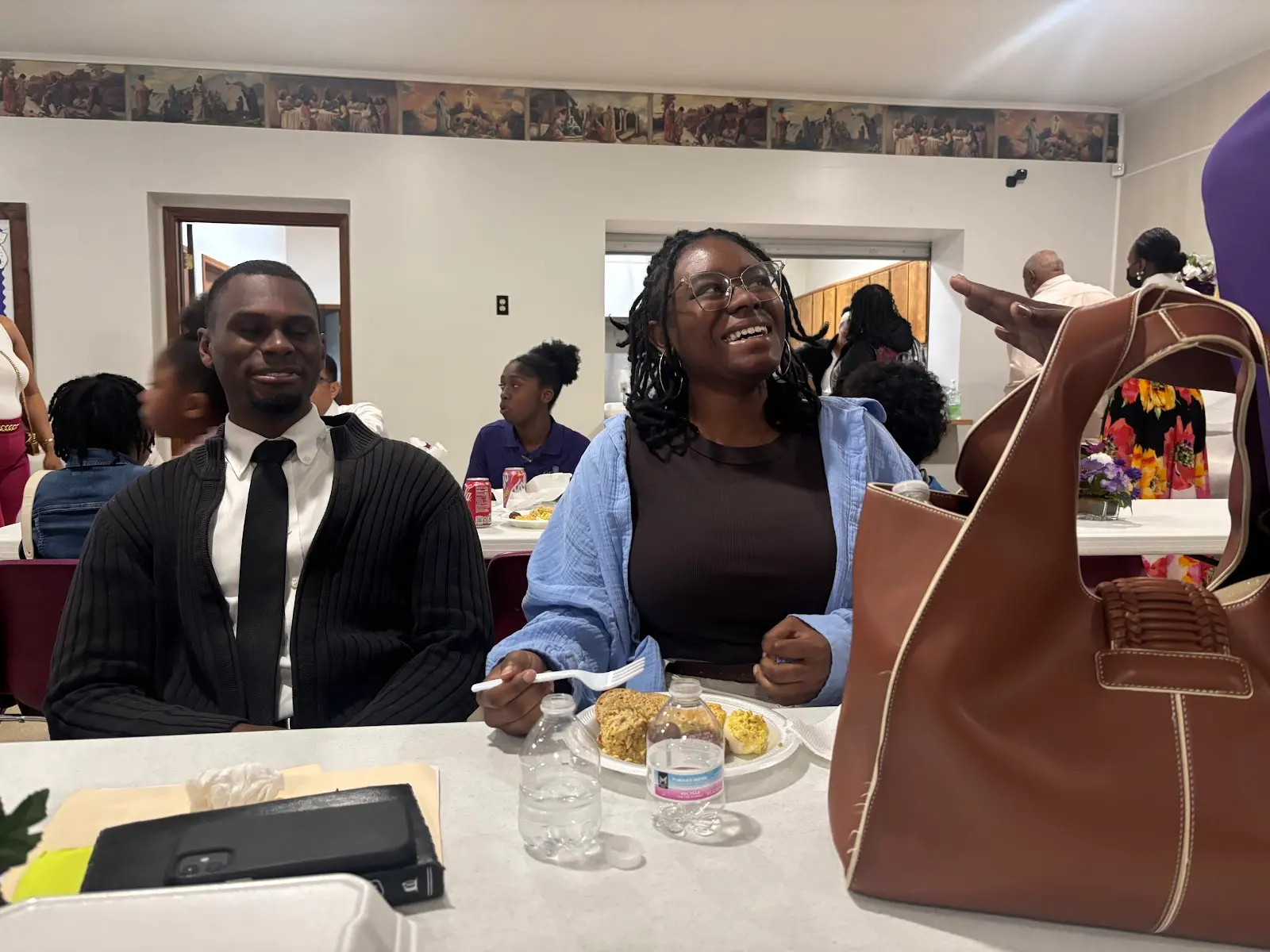 Members laughing together over a meal in the fellowship hall