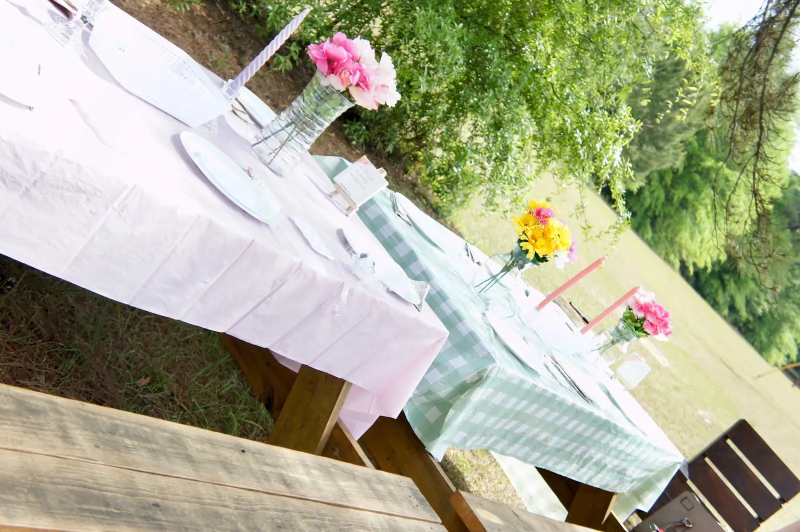 Picnic tables set with gingham cloths and fresh flowers under the pines