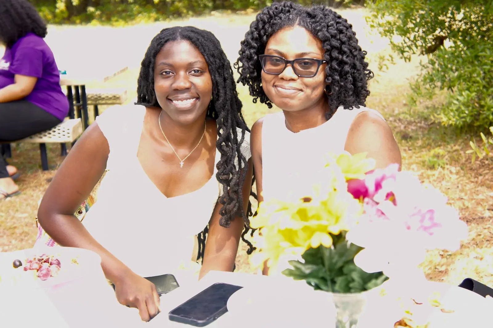 Two friends smiling together at the picnic table