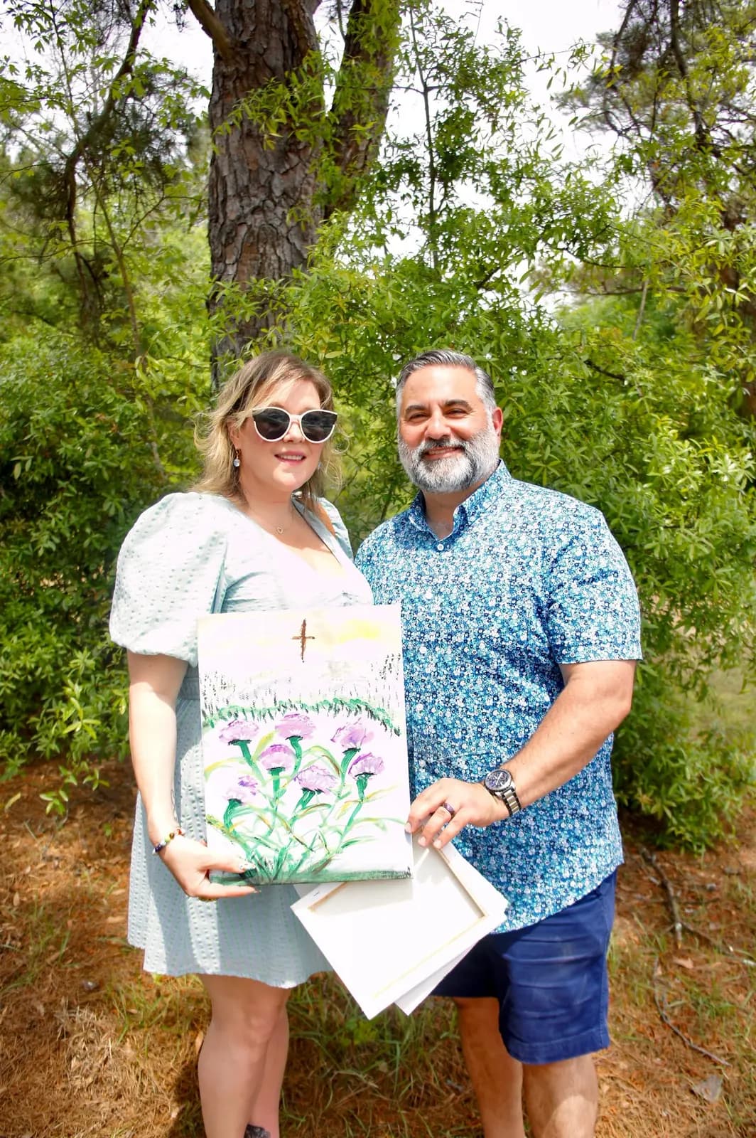 A couple holding up a flower painting at the spring picnic